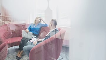 Man och kvinna sitter i röd kontorssoffa