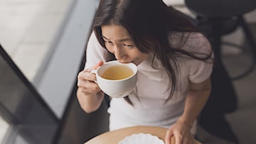 Kvinna dricker ur tekopp på café